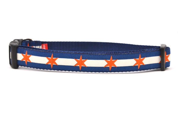 Large dog collar has two outer dark blue stripes and one central off-white stripe and orange six point stars around the collar. 