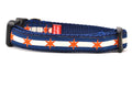 Small dog collar has two outer dark blue stripes and one central off-white stripe and orange six point stars around the collar. 