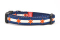 XS dog collar has two outer dark blue stripes and one central off-white stripe and orange six point stars around the collar. 