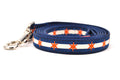 Small dog leash has two outer dark blue stripes and one central off-white stripe and orange six point stars around the collar. 