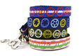 Stack of four dog leashes with bicycle sprocket designs.  One is pink with red, white, and green stripes and gray sprockets.  One is green with light green stripe and white, light green, and light blue sprockets.  One is navy with yellow, purple, and gray sprockets.  One has the colors of the colorado flag.