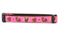 Large pink dog collar - design includes squirrel in lucha libre mask with a yellow flower behind it and a tulip on the mask.  One small squirrel with a tulip in its mough and one with a tulip bulb.  Also, a six pointed star.