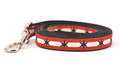 Small dog leash has two outer red stripes and one central off-white stripe and black six point stars around the collar. 