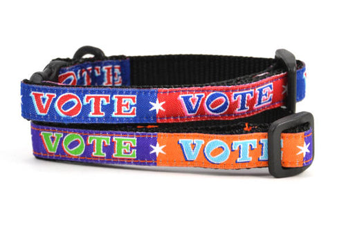 Two cat collars shown stacked.  One is red and navy blocks pattern with the word VOTE on each color block.  One is purple and orange blocks pattern with the word VOTE on each color block.  